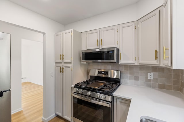 8517 Columbus Ave S, Bloomington, MN 55420 - kitchen featuring appliances with stainless steel finishes, light countertops, decorative backsplash, and light wood-style floors