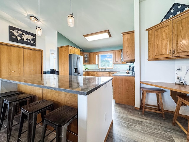 48285 229th Ave, Clearbrook, MN 56634 - kitchen with stainless steel fridge with ice dispenser, lofted ceiling, a breakfast bar area, wood finished floors, and brown cabinetry