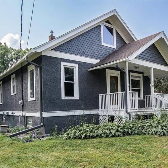 20 12th St NE, Rochester, MN 55906 - view of side of home with a yard, a chimney, covered porch, and stucco siding