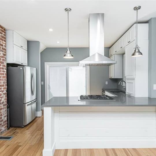 20 12th St NE, Rochester, MN 55906 - kitchen featuring stainless steel appliances, island exhaust hood, light wood-style flooring, a peninsula, and white cabinets