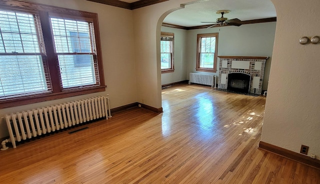 5015 17th Ave S, Minneapolis, MN 55417 - unfurnished living room with radiator, ornamental molding, arched walkways, ceiling fan, and light wood finished floors