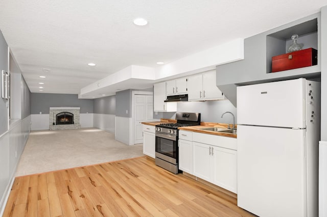 11735 52nd Ave N, Plymouth, MN 55442 - kitchen featuring freestanding refrigerator, gas stove, light wood-type flooring, under cabinet range hood, and white cabinetry