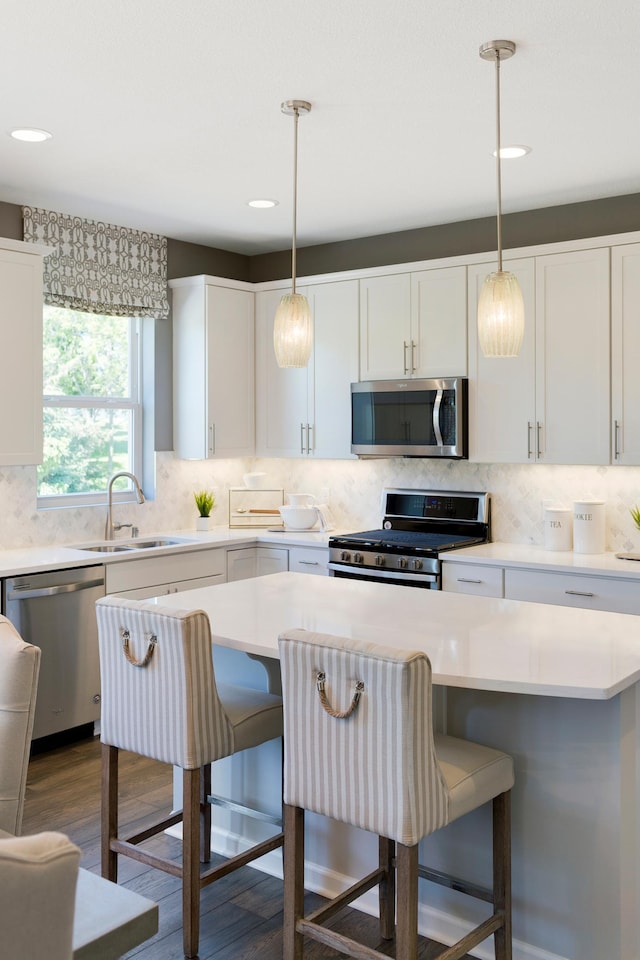 14620 106th Pl N, Maple Grove, MN 55369 - kitchen featuring appliances with stainless steel finishes, a kitchen breakfast bar, tasteful backsplash, light countertops, and recessed lighting