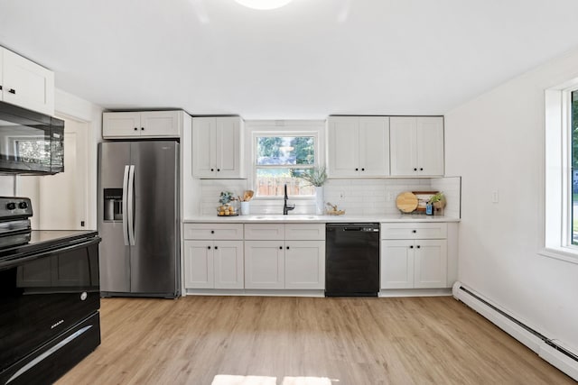 26030 2nd St W, Zimmerman, MN 55398 - kitchen with black appliances, a baseboard radiator, light wood-style flooring, tasteful backsplash, and light countertops