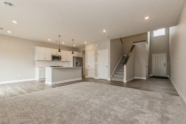 20019 62nd Pl, Corcoran, MN 55340 - unfurnished living room featuring light wood finished floors, recessed lighting, light colored carpet, and stairs