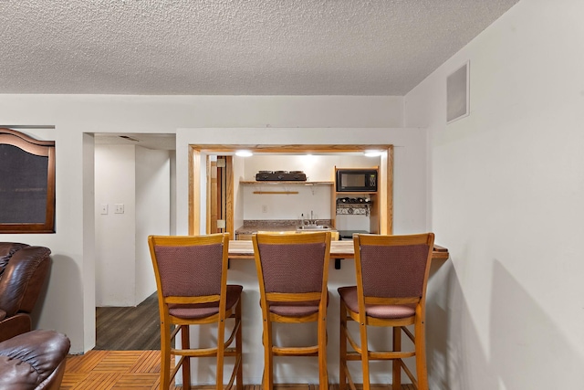 1682 Oakdale Ave W, Saint Paul, MN 55118 - dining area with wet bar, a textured ceiling, and wood finished floors