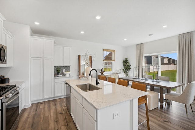 10663 Hemingway Ave S, Cottage Grove, MN 55016 - kitchen with appliances with stainless steel finishes, dark wood-type flooring, a center island with sink, white cabinets, and recessed lighting