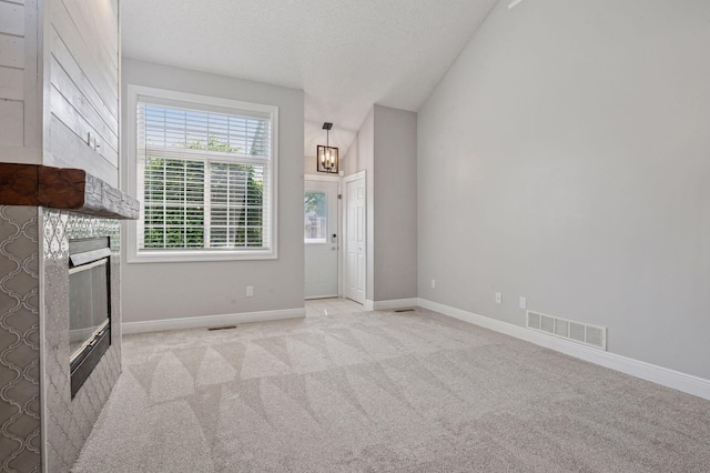 18347 Coneflower Ln, Eden Prairie, MN 55346 - unfurnished living room with a glass covered fireplace, carpet flooring, a chandelier, a textured ceiling, and vaulted ceiling