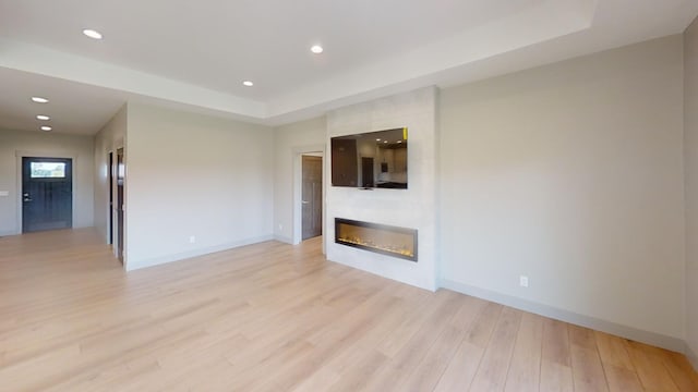 2334 9th St W, Albert Lea, MN 56007 - unfurnished living room featuring light wood finished floors, a tray ceiling, a fireplace, and recessed lighting