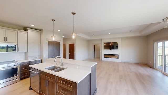 2334 9th St W, Albert Lea, MN 56007 - kitchen with appliances with stainless steel finishes, light wood-style floors, recessed lighting, pendant lighting, and a large fireplace