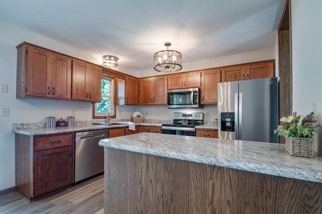 5445 Large Ave NE, Albertville, MN 55301 - kitchen with appliances with stainless steel finishes, a peninsula, light wood-style flooring, a chandelier, and brown cabinets
