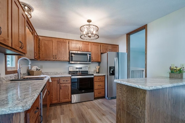 5445 Large Ave NE, Albertville, MN 55301 - kitchen featuring appliances with stainless steel finishes, brown cabinetry, light wood-type flooring, and a chandelier