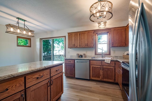 5445 Large Ave NE, Albertville, MN 55301 - kitchen featuring stainless steel appliances, brown cabinetry, plenty of natural light, light wood-style flooring, and a textured ceiling