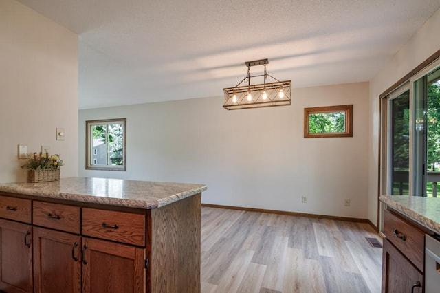5445 Large Ave NE, Albertville, MN 55301 - kitchen featuring light wood-style floors, brown cabinetry, a peninsula, light stone counters, and decorative light fixtures