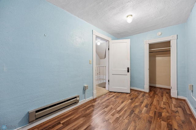 362 5th Ave N, Casselton, ND 58012 - unfurnished bedroom featuring a baseboard heating unit, wood finished floors, a textured ceiling, a closet, and a textured wall