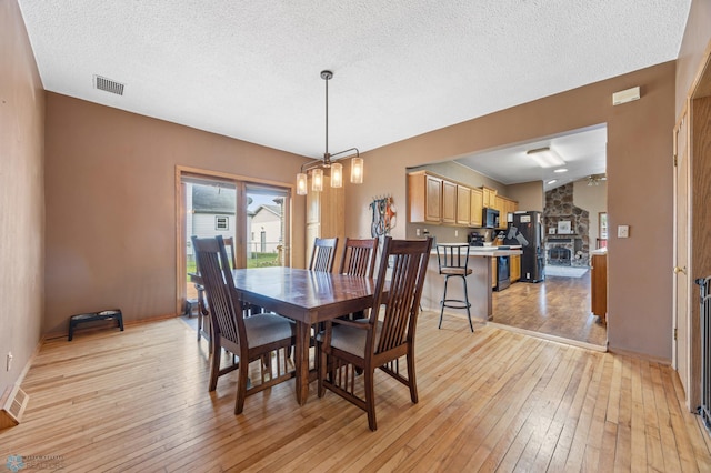 362 5th Ave N, Casselton, ND 58012 - dining area with light wood finished floors, a textured ceiling, and a fireplace