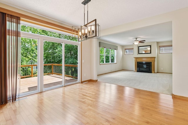 1767 Switchgrass Ct, Shakopee, MN 55379 - unfurnished living room featuring wood finished floors, ceiling fan, a glass covered fireplace, a chandelier, and a textured ceiling