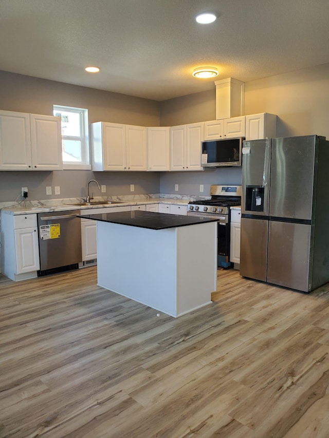1884 Ames Ave, Saint Paul, MN 55119 - kitchen featuring appliances with stainless steel finishes, white cabinets, light wood finished floors, a kitchen island, and recessed lighting