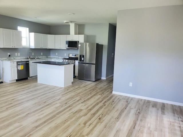 1884 Ames Ave, Saint Paul, MN 55119 - kitchen with appliances with stainless steel finishes, white cabinetry, light wood finished floors, and a kitchen island