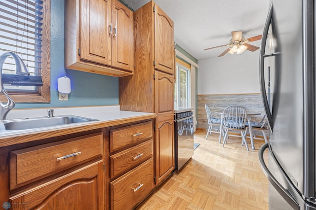 901 7th St W, West Fargo, ND 58078 - kitchen featuring appliances with stainless steel finishes, ceiling fan, a wainscoted wall, light countertops, and brown cabinetry