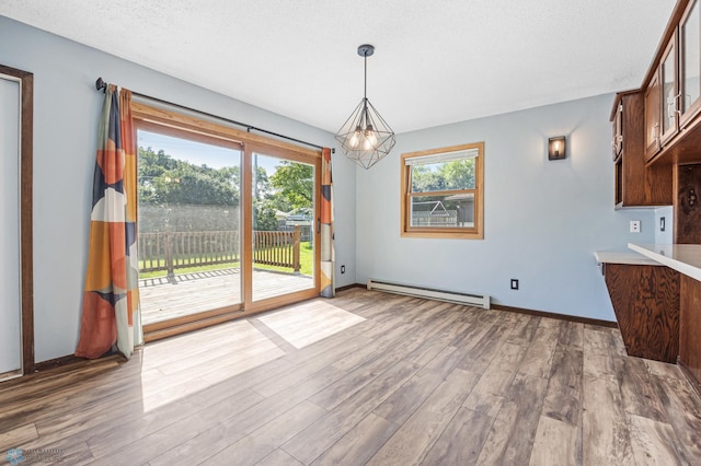 3113 8th St N, Fargo, ND 58102 - unfurnished dining area featuring a baseboard heating unit, wood finished floors, a chandelier, and a textured ceiling