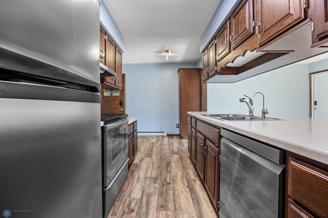 3113 8th St N, Fargo, ND 58102 - kitchen featuring stainless steel appliances, a baseboard heating unit, range hood, light countertops, and wood finished floors