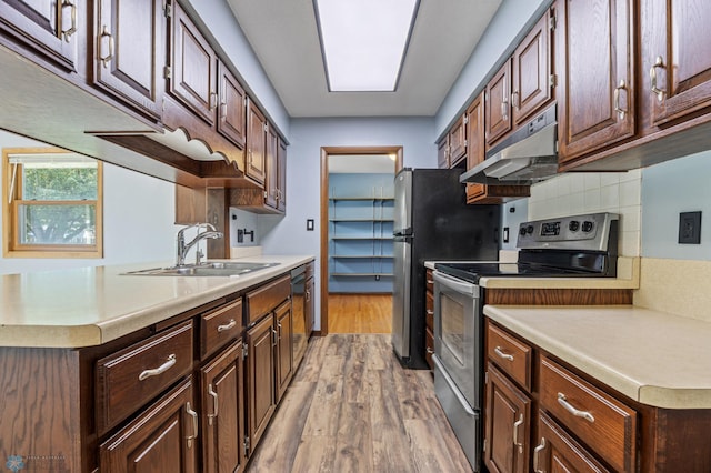 3113 8th St N, Fargo, ND 58102 - kitchen with appliances with stainless steel finishes, under cabinet range hood, light countertops, light wood-type flooring, and backsplash