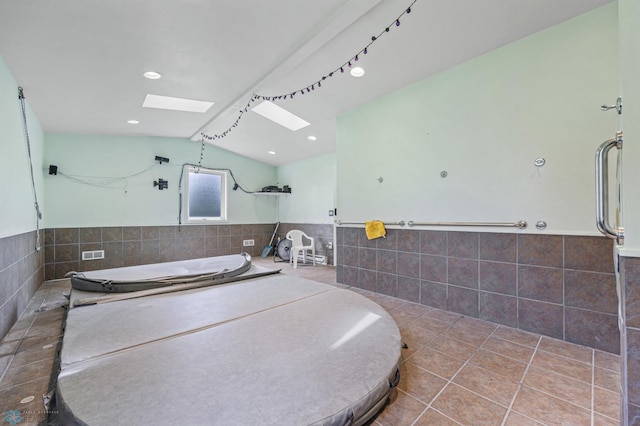 3113 8th St N, Fargo, ND 58102 - full bath featuring tile walls, lofted ceiling, a skylight, a wainscoted wall, and a garden tub