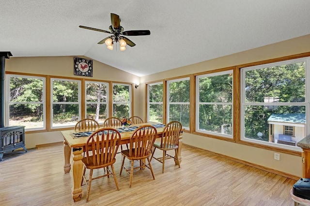 417 Whiskey Rd SW, Isanti, MN 55040 - dining area featuring a wood stove, light wood-style floors, vaulted ceiling, a textured ceiling, and ceiling fan