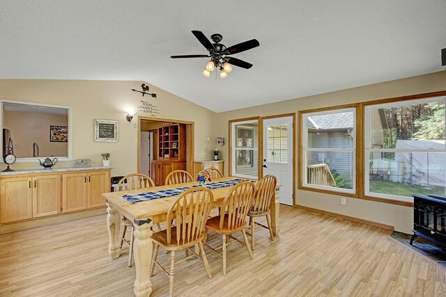 417 Whiskey Rd SW, Isanti, MN 55040 - dining space featuring vaulted ceiling, light wood-style flooring, a wood stove, and a ceiling fan