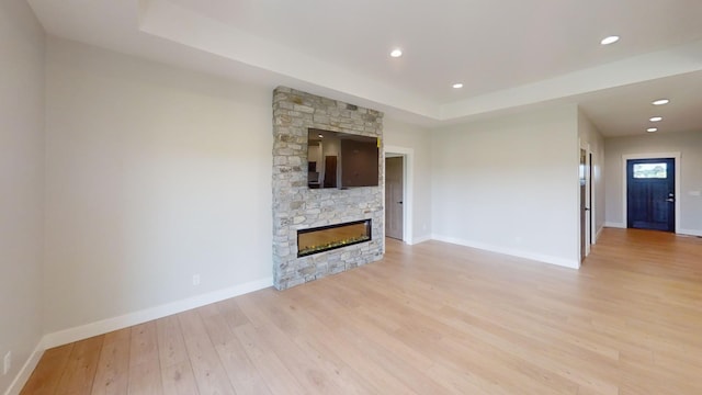 2330 9th St W, Albert Lea, MN 56007 - unfurnished living room featuring a tray ceiling, light wood finished floors, a stone fireplace, and recessed lighting