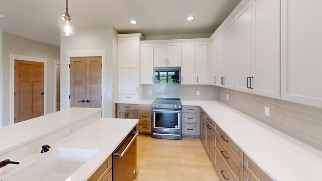 2330 9th St W, Albert Lea, MN 56007 - kitchen with appliances with stainless steel finishes, light wood-style floors, decorative light fixtures, light countertops, and decorative backsplash