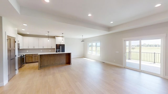 2330 9th St W, Albert Lea, MN 56007 - kitchen featuring refrigerator with ice dispenser, open floor plan, decorative backsplash, a kitchen island, and light wood-style flooring