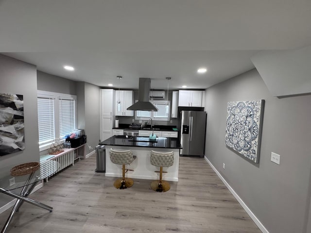 4644 Lyndale Ave S, Minneapolis, MN 55419 - kitchen with stainless steel fridge, island exhaust hood, light wood-style flooring, dark countertops, and white cabinetry