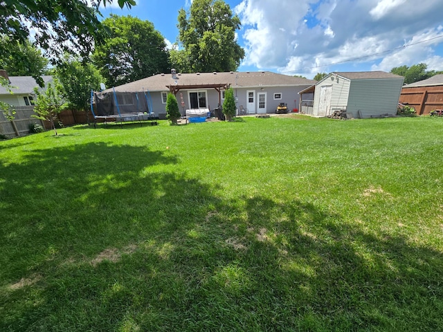 1101 7th Ave SW, Pipestone, MN 56164 - back of house featuring a trampoline, a fenced backyard, and a storage unit