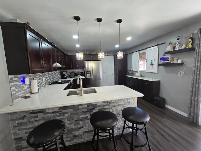 1101 7th Ave SW, Pipestone, MN 56164 - kitchen featuring stainless steel appliances, a peninsula, light countertops, dark wood-style floors, and tasteful backsplash