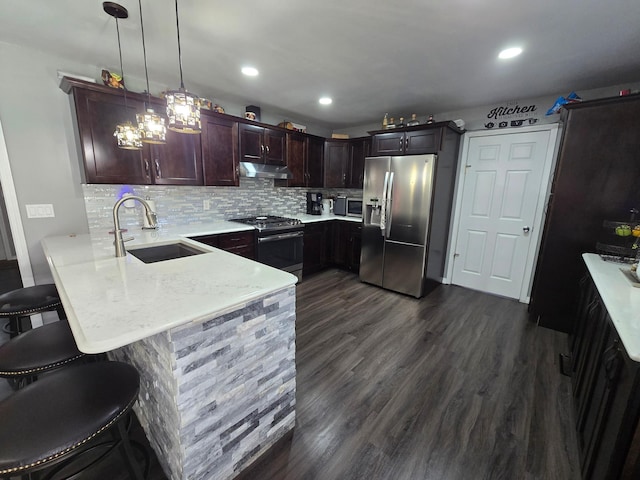 1101 7th Ave SW, Pipestone, MN 56164 - kitchen featuring appliances with stainless steel finishes, under cabinet range hood, a peninsula, a kitchen bar, and decorative backsplash