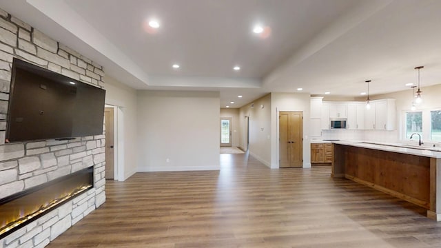 2329 9th St W, Albert Lea, MN 56007 - kitchen with stainless steel microwave, a fireplace, wood finished floors, open floor plan, and white cabinets
