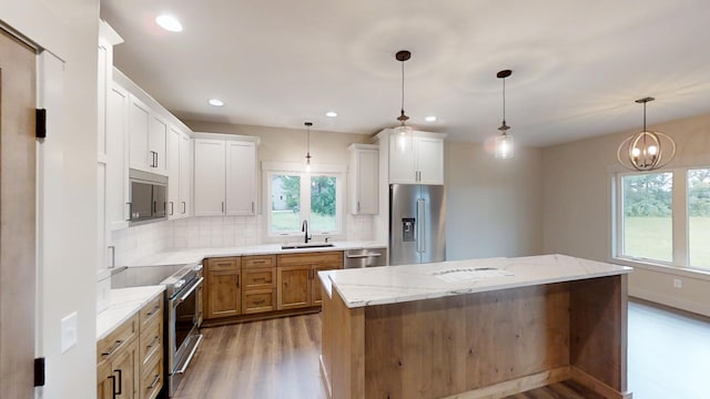 2329 9th St W, Albert Lea, MN 56007 - kitchen with high quality appliances, wood finished floors, decorative backsplash, a center island, and recessed lighting