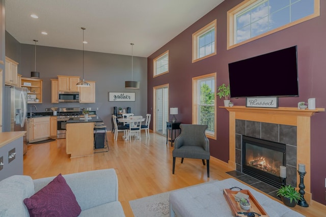 9742 Saint Andrews Dr, Elko New Market, MN 55020 - living area featuring a towering ceiling, light wood-style floors, a tiled fireplace, plenty of natural light, and recessed lighting