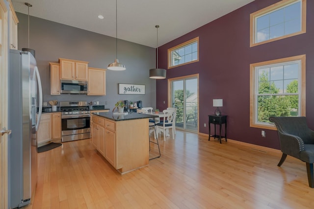 9742 Saint Andrews Dr, Elko New Market, MN 55020 - kitchen featuring appliances with stainless steel finishes, light brown cabinets, a towering ceiling, dark countertops, and a breakfast bar