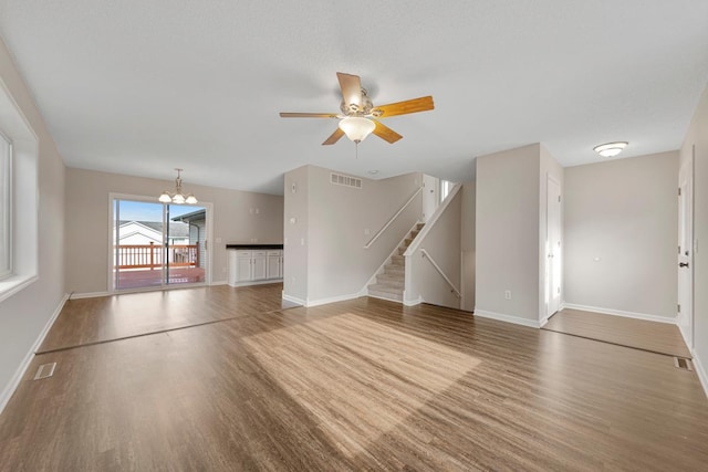 2112 York St, Saint Peter, MN 56082 - unfurnished living room with wood finished floors, ceiling fan, a chandelier, and stairway