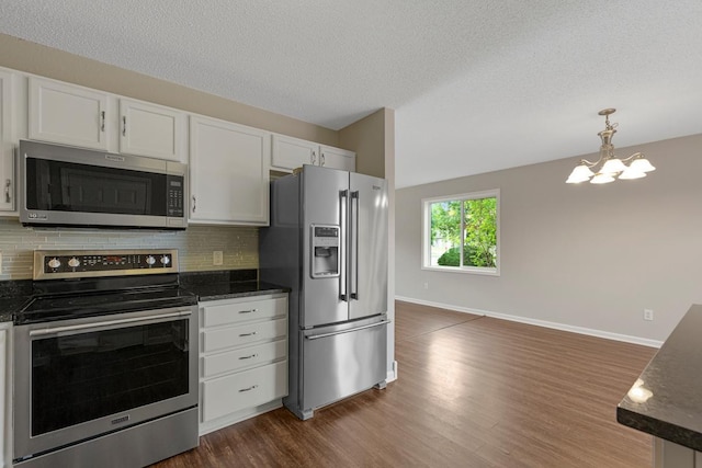 2112 York St, Saint Peter, MN 56082 - kitchen with stainless steel appliances, dark wood-style flooring, backsplash, a chandelier, and white cabinets
