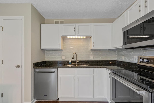 2112 York St, Saint Peter, MN 56082 - kitchen featuring stainless steel appliances, white cabinets, decorative backsplash, dark stone counters, and a textured ceiling