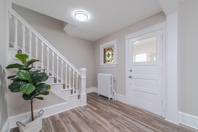 2156 Saint Anthony Ave, Saint Paul, MN 55104 - entrance foyer with radiator, wood finished floors, stairs, and a textured ceiling