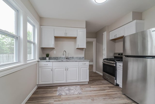 2156 Saint Anthony Ave, Saint Paul, MN 55104 - kitchen featuring stainless steel appliances, white cabinetry, light wood-type flooring, and light stone counters