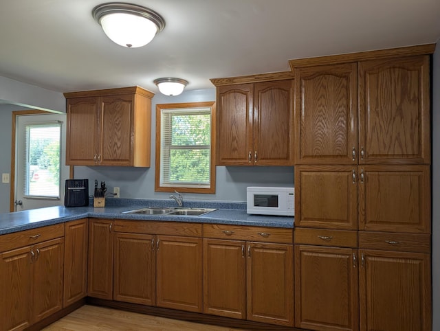 202 Hill St, Russell, MN 56169 - kitchen featuring white microwave, brown cabinetry, dark countertops, and light wood-type flooring
