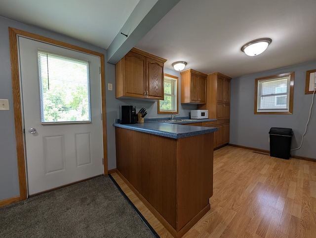 202 Hill St, Russell, MN 56169 - kitchen with a peninsula, brown cabinets, dark countertops, white microwave, and light wood-style floors