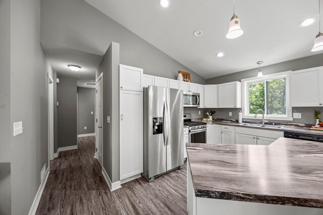 13143 Jefferson St, Becker, MN 55308 - kitchen featuring appliances with stainless steel finishes, vaulted ceiling, wood finished floors, dark countertops, and white cabinetry