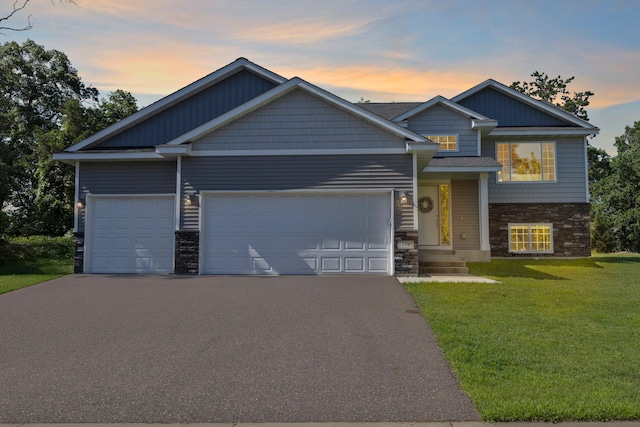 13143 Jefferson St, Becker, MN 55308 - view of front of house featuring asphalt driveway, stone siding, an attached garage, and a yard